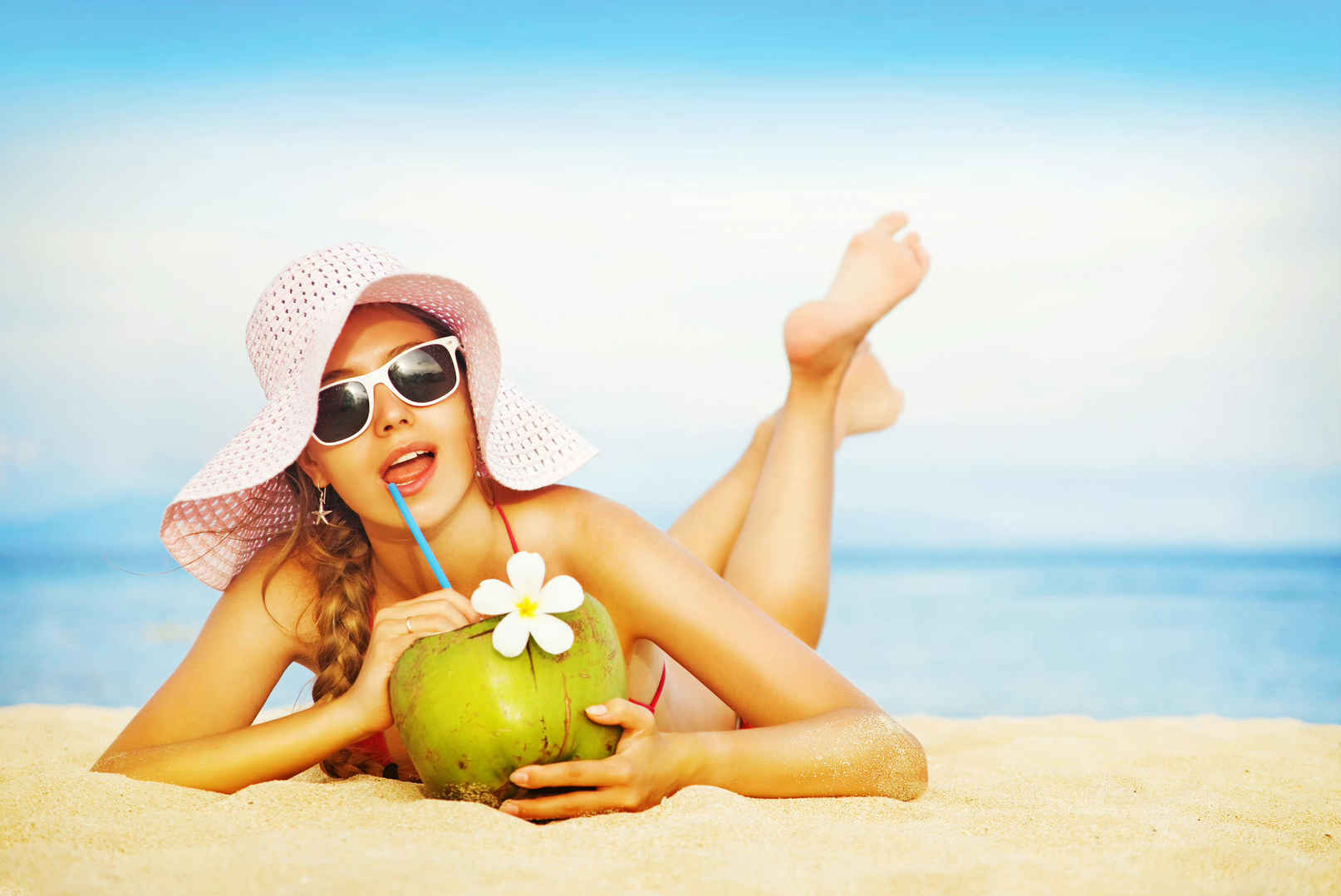 夏天美女趴在沙滩上喝椰汁-