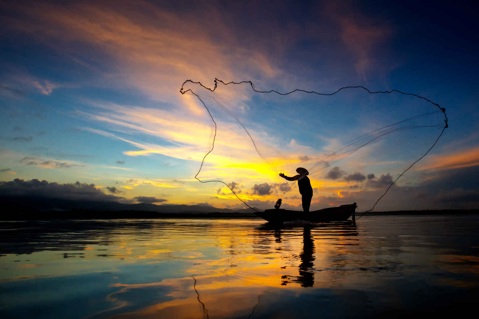 渔民清晨在湖边用网抓鱼的剪影-
