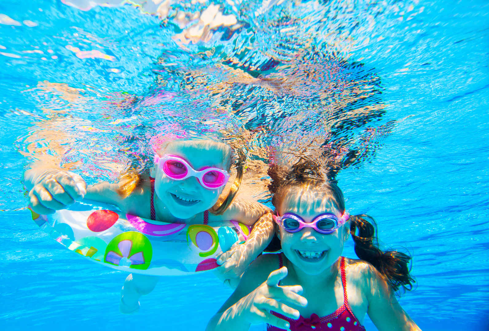 游泳池里两个小女孩微笑玩撒图片-
