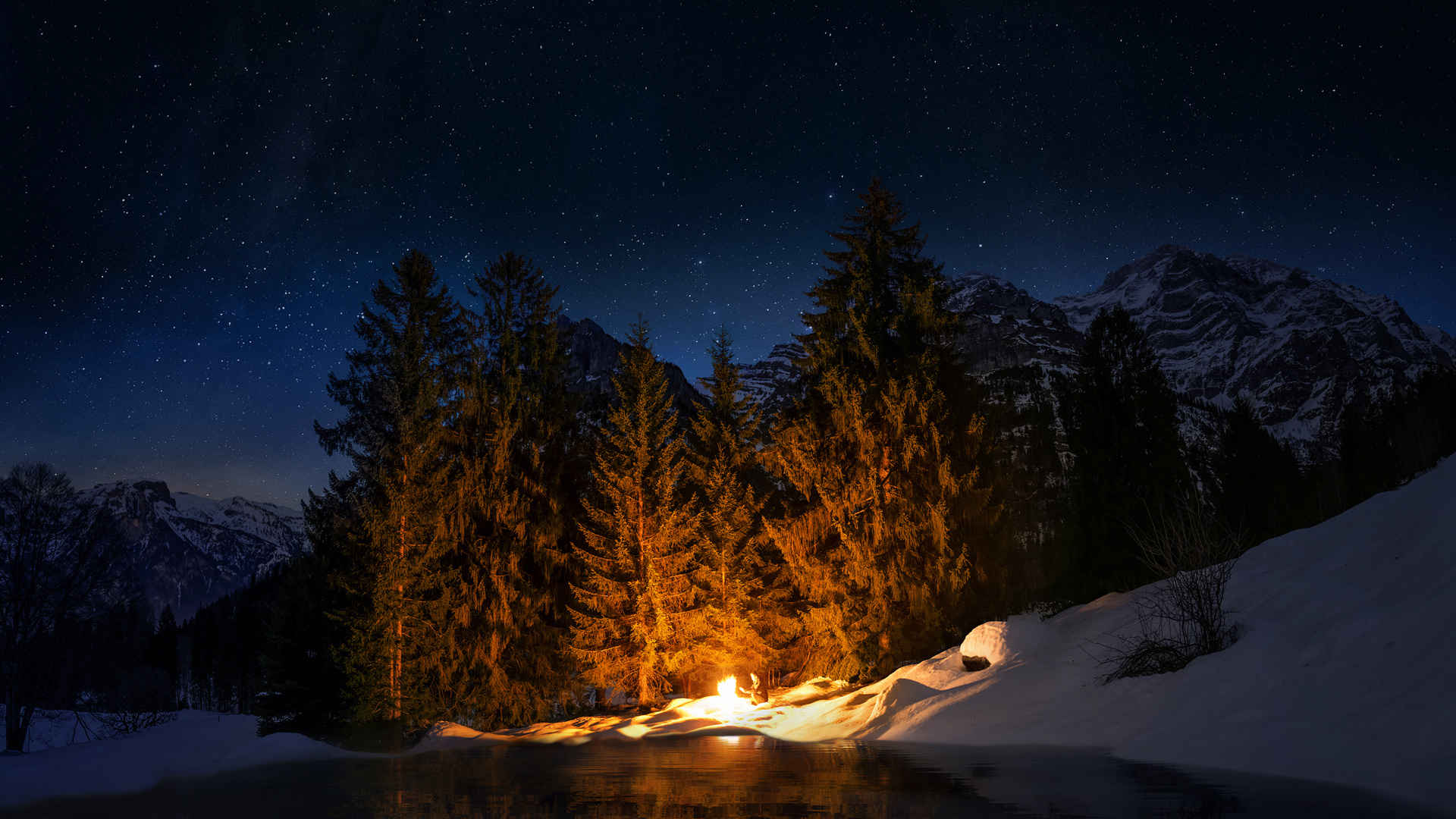 夜晚一个人在雪山里起火取暖-