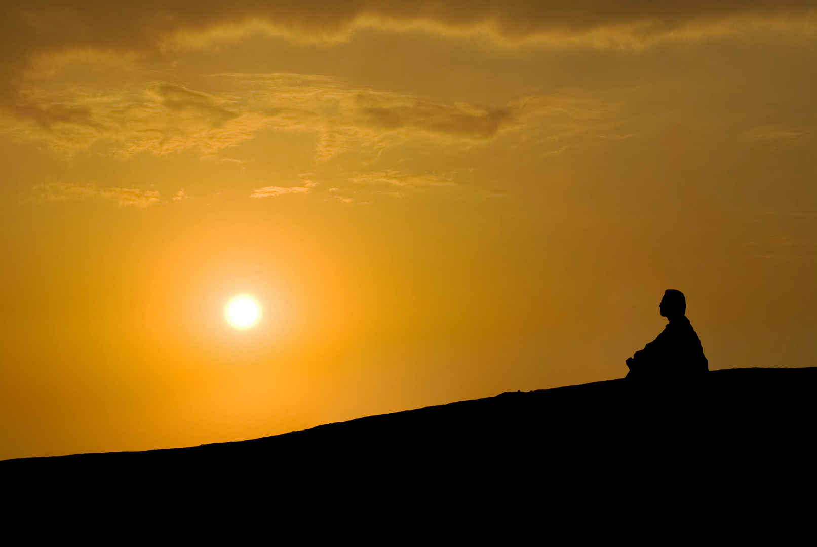 日落坐在山坡上的人冥想风景图-