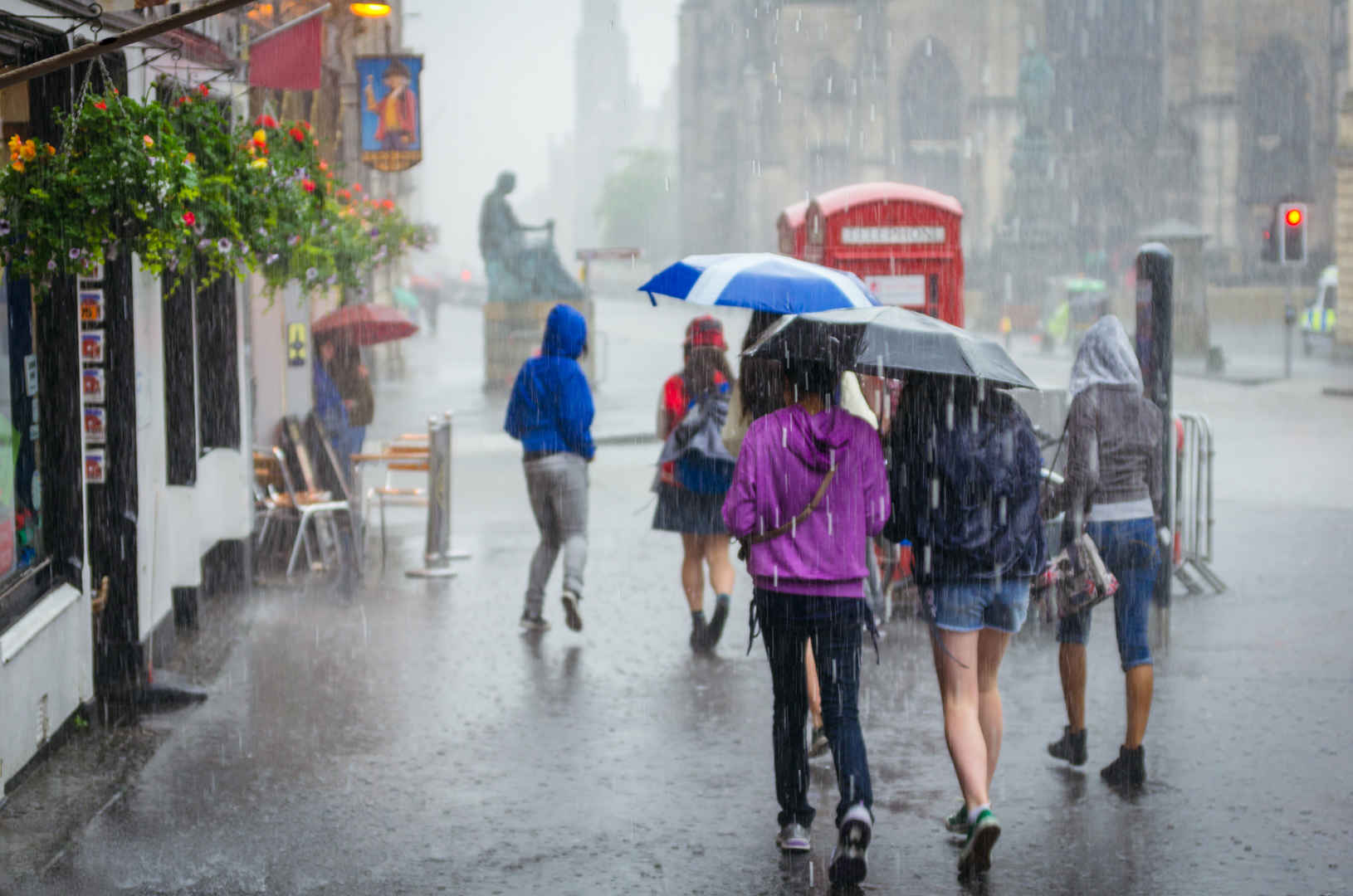 街道上一群女孩在雨中举着雨伞匆匆忙忙的走着