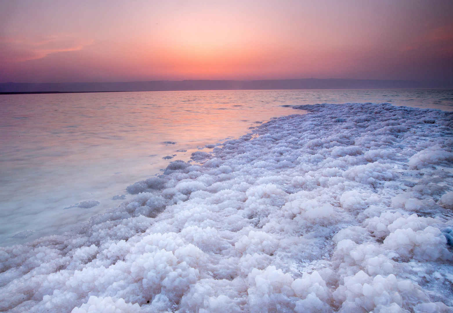夕阳下死海旁边堆积的盐结晶-