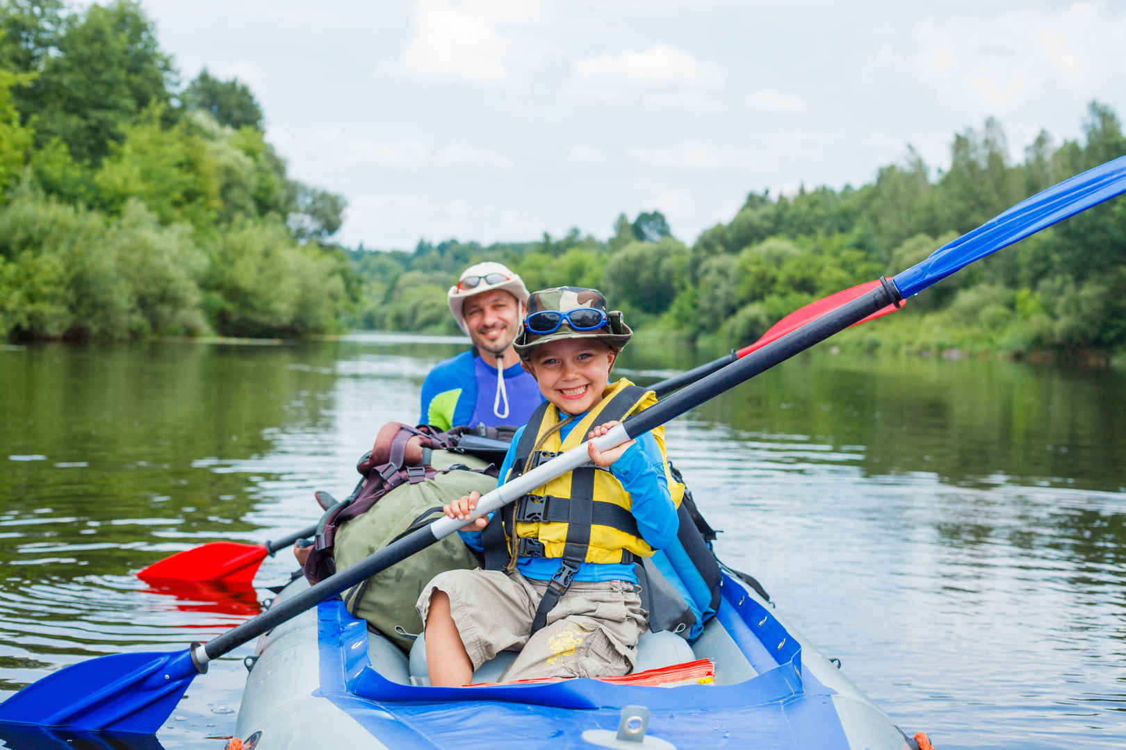 暑假里一名快乐小男孩与他的父亲在河上划着划艇