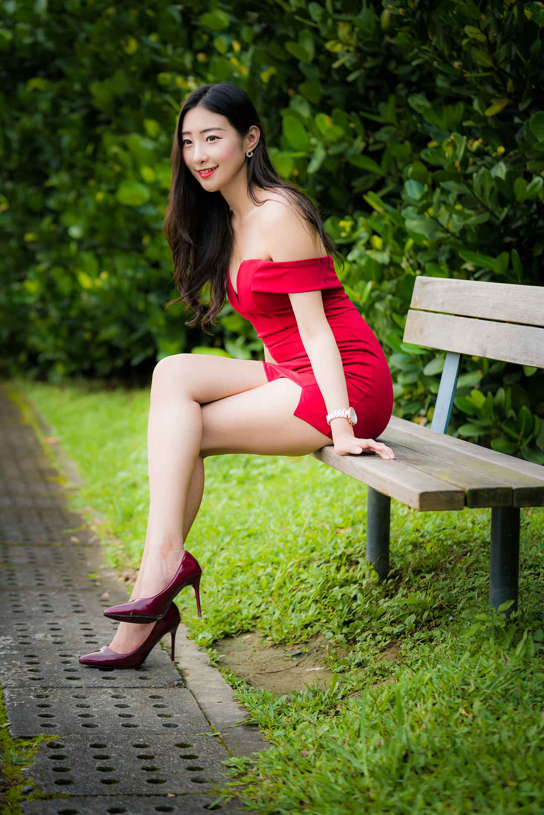坐在长椅上的大长腿高跟红裙微笑女孩手机壁纸