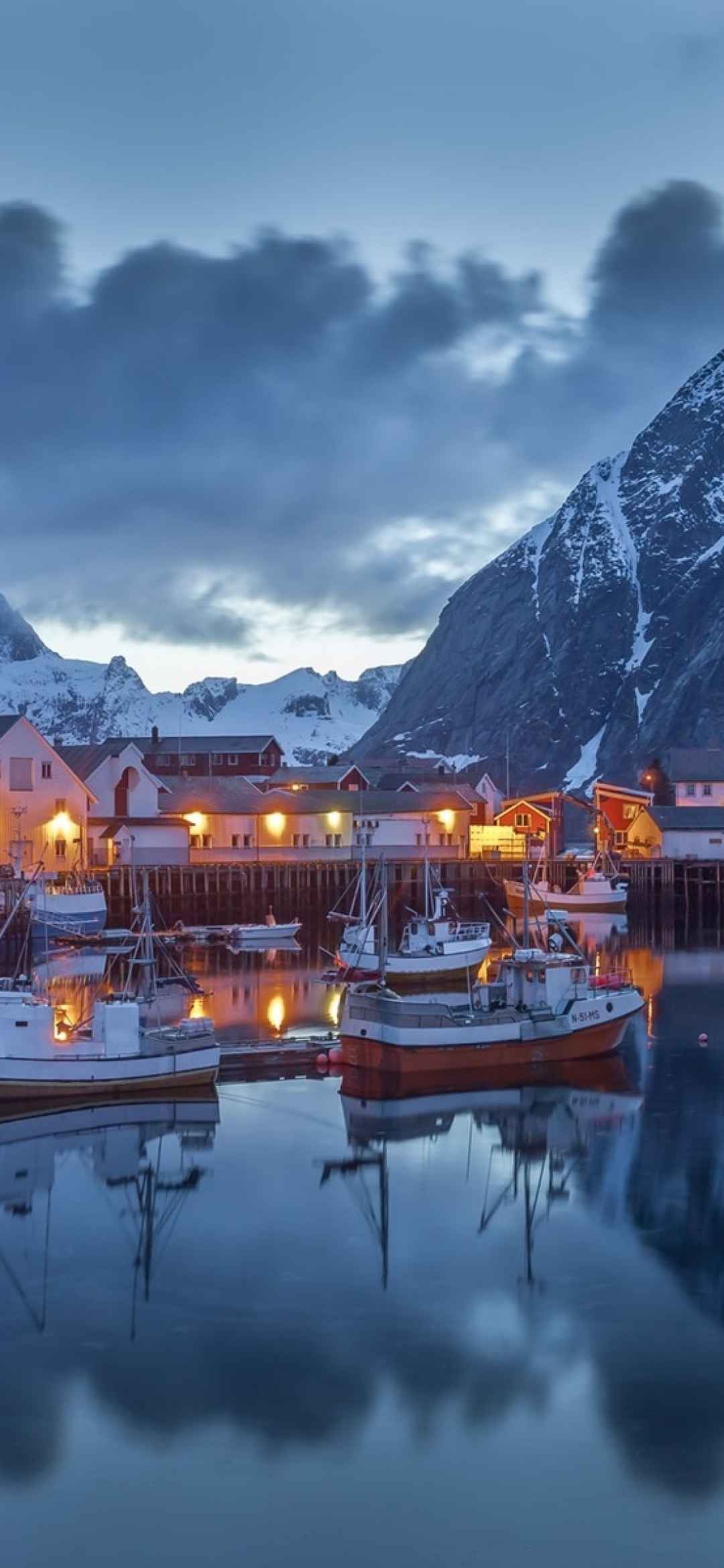寒冷的雪山地带，山下小镇亮起灯光的欧式建筑和湖中的小船手机壁纸