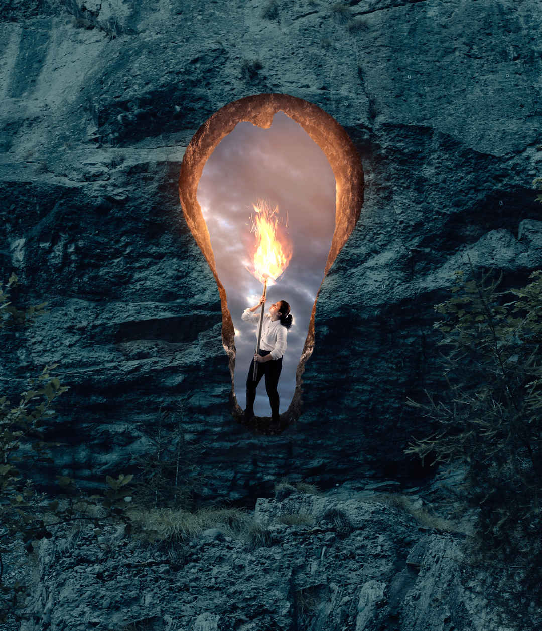 手持火炬的女子在岩石墙上的灯泡形状的洞-