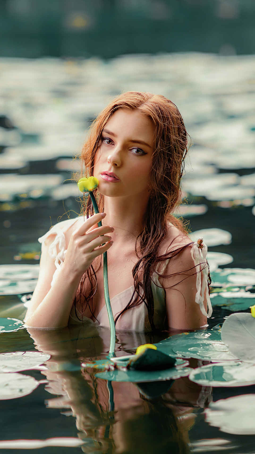 池塘中拿花的金发美女